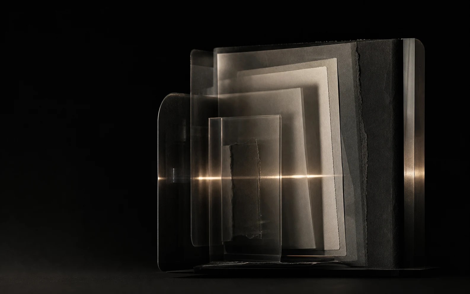 Schichten aus dunklem Papier und Glas, durchzogen von einer schmalen Lichtspur